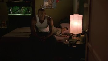 Movie still from “Baby Boy” (2001), directed by John Singleton – A man sitting on a bed next to a sleeping child; Medium shot, Low angle