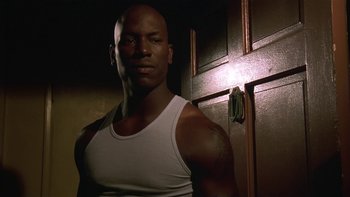 Movie still from “Baby Boy” (2001), directed by John Singleton – A man in a white tank top standing in front of a door; Close Up shot, Low angle