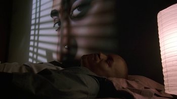 Movie still from “Baby Boy” (2001), directed by John Singleton – A man laying in a bed next to a wall with an image of a man's face on it; Extreme Close Up shot, High angle