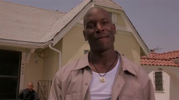 Movie still from “Baby Boy” (2001), directed by John Singleton – A man standing in front of a house smiling for the camera; Close Up shot, Low angle