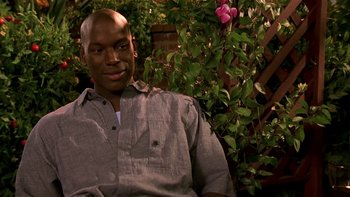 Movie still from “Baby Boy” (2001), directed by John Singleton – A man sitting on a chair in front of a flower bush; Close Up shot, High angle