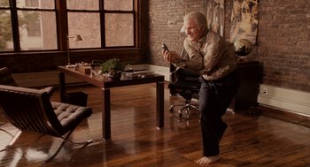 Movie still from “Baby Mama” (2008), directed by Michael McCullers – An older man sitting on the floor looking at his cell phone; Wide shot, High angle