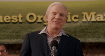 Movie still from “Baby Mama” (2008), directed by Michael McCullers – A man with a microphone in front of an organic sign in the background; Close Up shot, Low angle