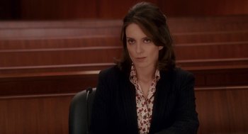 Movie still from “Baby Mama” (2008), directed by Michael McCullers – A woman sitting in a chair in front of a wooden wall; Medium shot, Over the shoulder angle