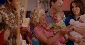 Movie still from “Baby Mama” (2008), directed by Michael McCullers – A woman holding a baby in her arms and laughing; Medium shot, Over the shoulder angle