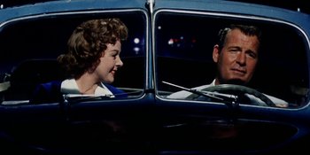 Movie still from “Back Street” (1961), directed by David Miller – A man and a woman sitting in the back seat of a car; Medium shot, Low angle