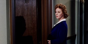 Movie still from “Back Street” (1961), directed by David Miller – A woman standing in front of a wooden door; Close Up shot, Over the shoulder angle