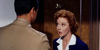 Movie still from “Back Street” (1961), directed by David Miller – A woman in a blue and white dress is talking to a man in a military uniform; Close Up shot, Over the shoulder angle