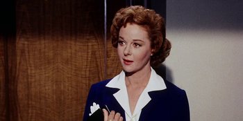 Movie still from “Back Street” (1961), directed by David Miller – A woman in a blue jacket holding a cigarette holder; Close Up shot, Low angle