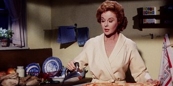 Movie still from “Back Street” (1961), directed by David Miller – A woman in a kitchen preparing food on a pan; Medium shot, Low angle