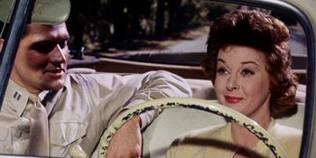 Movie still from “Back Street” (1961), directed by David Miller – A woman sitting in the driver's seat of a car; Close Up shot, Over the shoulder angle