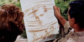 Movie still from “Back Street” (1961), directed by David Miller – A person holding a painting of a man's face in the grass; Extreme Close Up shot, Low angle