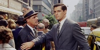 Movie still from “Back Street” (1961), directed by David Miller – A man in a suit and a man in a hat; Medium shot, Over the shoulder angle