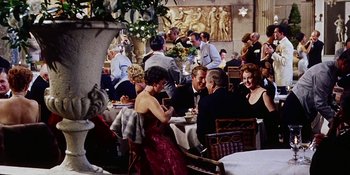 Movie still from “Back Street” (1961), directed by David Miller – A group of people sitting at a table in a restaurant; Wide shot, High angle