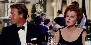 Movie still from “Back Street” (1961), directed by David Miller – A man and a woman sitting at a dinner table; Medium shot, Over the shoulder angle