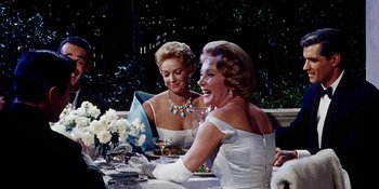 Movie still from “Back Street” (1961), directed by David Miller – Two women sitting at a dinner table talking to each other; Medium shot, Over the shoulder angle