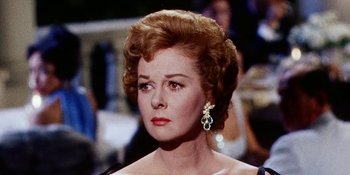 Movie still from “Back Street” (1961), directed by David Miller – An older woman wearing a black dress and a gold and diamond earring; Close Up shot, Over the shoulder angle