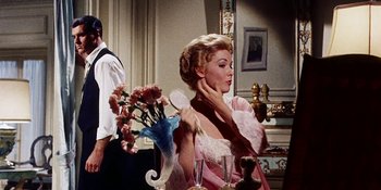 Movie still from “Back Street” (1961), directed by David Miller – A woman in a pink dress sitting in front of a mirror; Medium shot, Over the shoulder angle