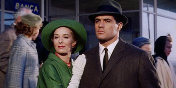 Movie still from “Back Street” (1961), directed by David Miller – A man and a woman wearing hats and suits; Medium shot, Low angle