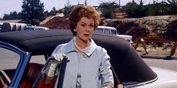 Movie still from “Back Street” (1961), directed by David Miller – An older woman in a blue dress and white gloves holding a purse; Medium shot, Low angle