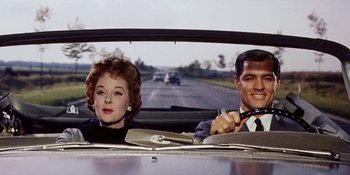Movie still from “Back Street” (1961), directed by David Miller – An older woman and a younger man in the back seat of a car; Medium shot, Low angle
