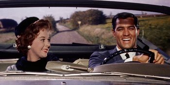 Movie still from “Back Street” (1961), directed by David Miller – A man and a woman sitting in the back seat of a car; Medium shot, Low angle
