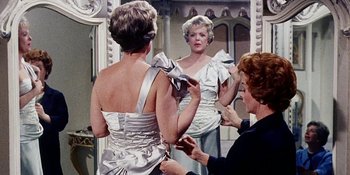 Movie still from “Back Street” (1961), directed by David Miller – An older woman looking in the mirror while a younger woman adjusts her dress; Medium shot, Low angle