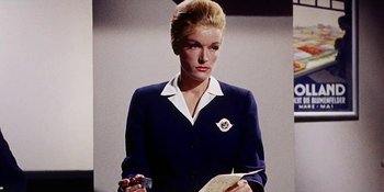 Movie still from “Back Street” (1961), directed by David Miller – A woman in a suit holding a pen and a book; Medium shot, Low angle