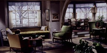 Movie still from “Back Street” (1961), directed by David Miller – A living room filled with lots of furniture and windows; Wide shot, High angle