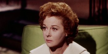 Movie still from “Back Street” (1961), directed by David Miller – An older woman with red curly hair sitting on a green couch; Close Up shot, High angle
