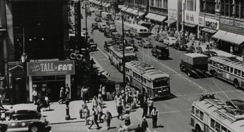 Movie still from “Back to School” (1986), directed by Alan Metter – An old photo of a busy city street with buses and cars; Extreme Wide shot, High angle