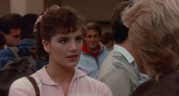 Movie still from “Back to School” (1986), directed by Alan Metter – A woman with a ponytail is standing in front of a group of people; Close Up shot, Over the shoulder angle