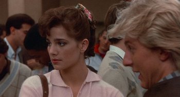 Movie still from “Back to School” (1986), directed by Alan Metter – A woman with a pink shirt is looking at the camera; Close Up shot, Over the shoulder angle