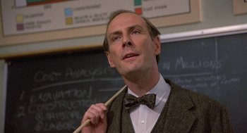 Movie still from “Back to School” (1986), directed by Alan Metter – A man in a suit and bow tie holding a wooden stick; Close Up shot, Low angle