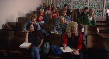 Movie still from “Back to School” (1986), directed by Alan Metter – A group of people sitting in a room with papers; Wide shot, High angle