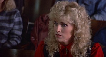 Movie still from “Back to School” (1986), directed by Alan Metter – A woman with long blonde curly hair sitting in a room; Close Up shot, Over the shoulder angle