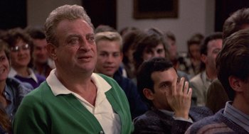 Movie still from “Back to School” (1986), directed by Alan Metter – A group of people sitting in a room; Close Up shot, Low angle