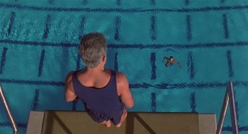 Movie still from “Back to School” (1986), directed by Alan Metter – An older man is watching a swimmer in the pool; Wide shot, Overhead angle