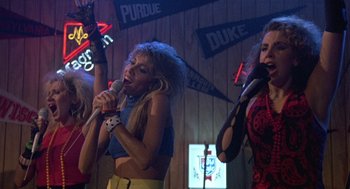 Movie still from “Back to School” (1986), directed by Alan Metter – A group of women singing into microphones in a bar; Medium shot, Low angle