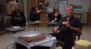Movie still from “Back to School” (1986), directed by Alan Metter – A group of people sitting around a box of pizza; Wide shot, High angle