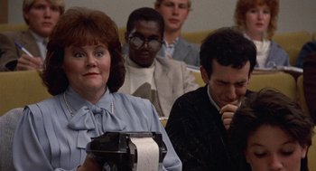 Movie still from “Back to School” (1986), directed by Alan Metter – A woman holding a roll of toilet paper in front of other people; Close Up shot, Over the shoulder angle