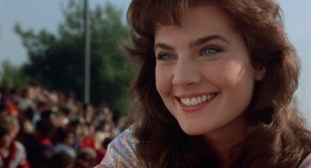 Movie still from “Back to School” (1986), directed by Alan Metter – A woman's face in front of a group of people; Close Up shot, Over the shoulder angle