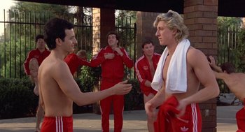 Movie still from “Back to School” (1986), directed by Alan Metter – A group of young men standing next to each other on a sidewalk; Medium shot, Low angle