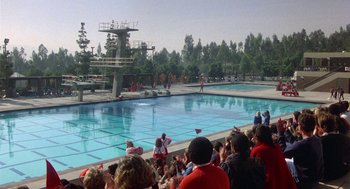 Movie still from “Back to School” (1986), directed by Alan Metter – A group of people standing in front of a swimming pool; Extreme Wide shot, High angle