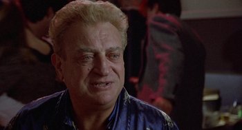 Movie still from “Back to School” (1986), directed by Alan Metter – An older man with blonde hair wearing a blue shirt; Close Up shot, Low angle