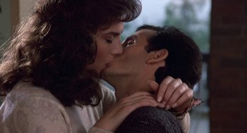 Movie still from “Back to School” (1986), directed by Alan Metter – A man and a woman kissing each other in front of a window; Close Up shot, Low angle