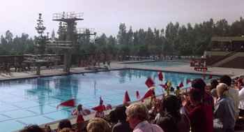 Movie still from “Back to School” (1986), directed by Alan Metter – A group of people standing next to a swimming pool; Extreme Wide shot, High angle