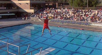 Movie still from “Back to School” (1986), directed by Alan Metter – A man jumping into a swimming pool while people watch; Extreme Wide shot, High angle