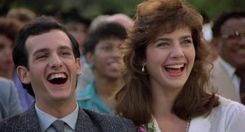 Movie still from “Back to School” (1986), directed by Alan Metter – A man and a woman laughing together in a crowd of onlookers; Close Up shot, Low angle