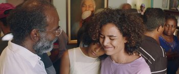 Two women and an older man in front of a painting
